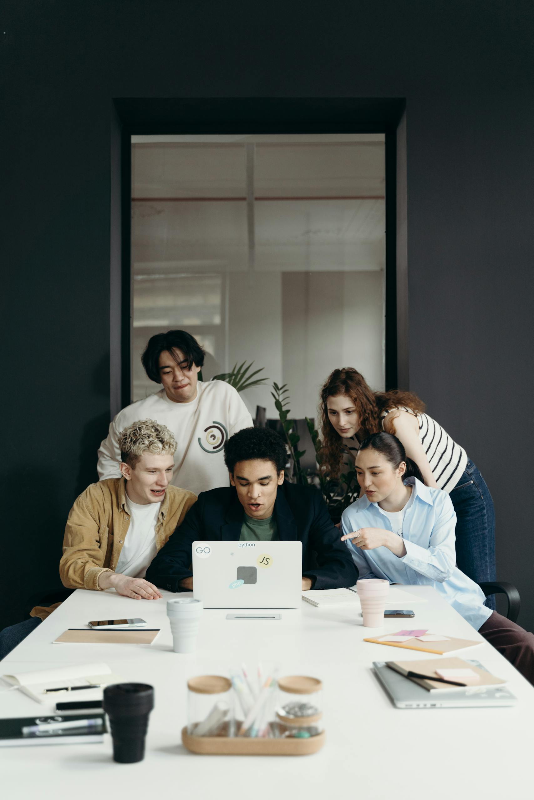 Young professionals brainstorming around a laptop in a contemporary office setting.